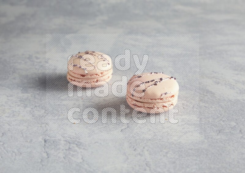 45º Shot of two pink orange blossom macarons  on white  marble background