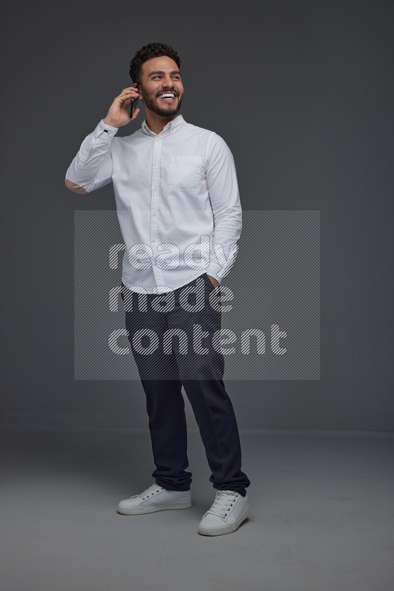 A man wearing smart casual talking in the phone eye level on a gray background