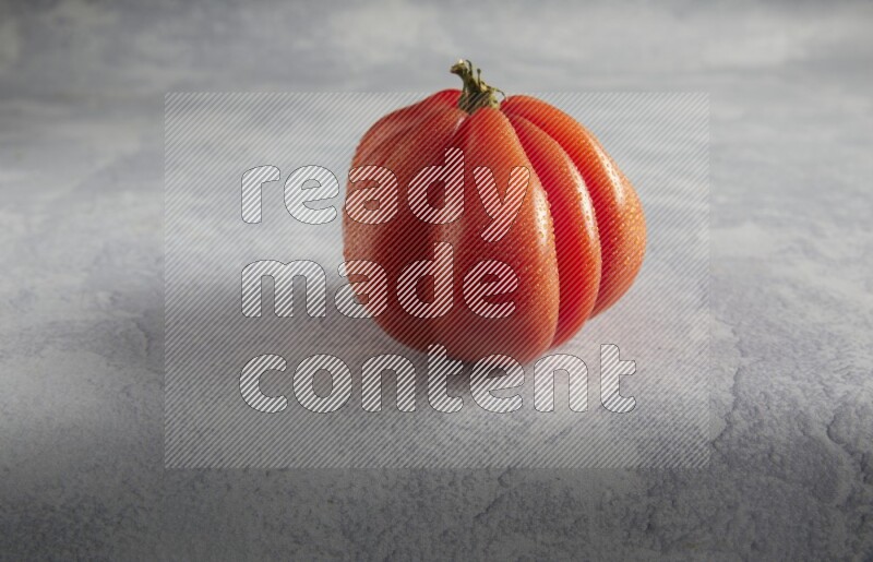 45 degree single heirloom tomato on a light blue textured background