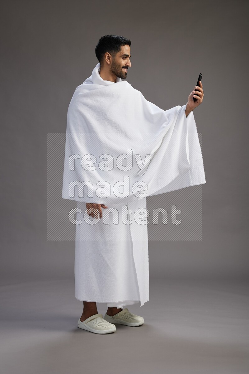 A man wearing Ehram Standing taking selfie on gray background