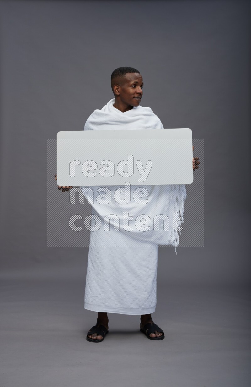 A man wearing Ehram Standing holding board sign on gray background