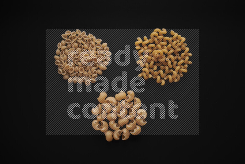 Different pasta types in bunches on black background
