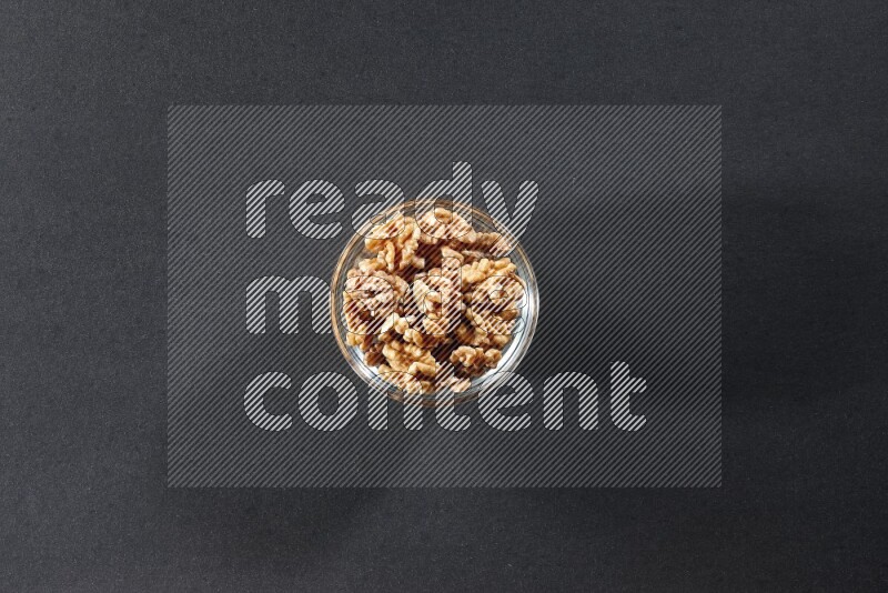 A glass bowl full of peeled walnuts on a black background in different angles