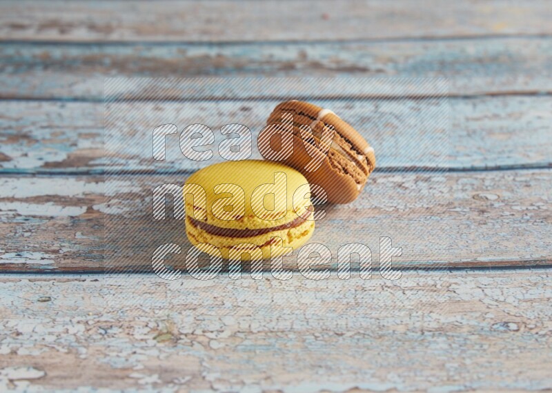 45º Shot of of two assorted Brown Irish Cream, and Yellow Lemon macarons on light blue background