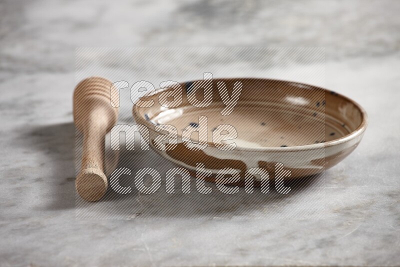 Multicolored pottery bowl with wooden honey dipper on the side on grey marble background