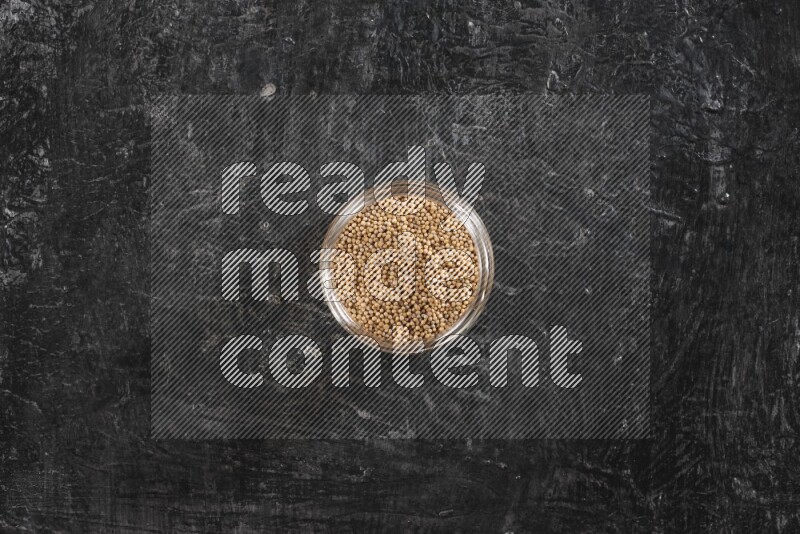 وعاء زجاجي ممتلئ ببذور الخردل على خلفية سوداء