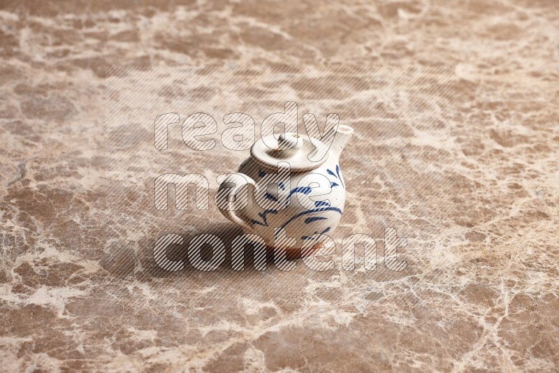 A pottery teapot on beige marble background