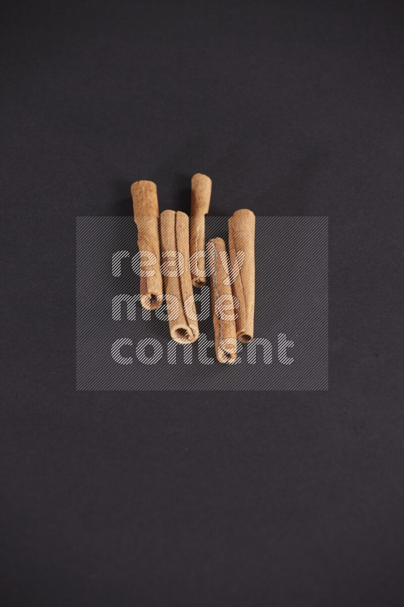 Cinnamon sticks stacked on black flooring