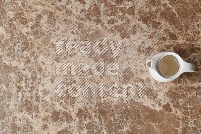 A ceramic milk jug on beige marble background