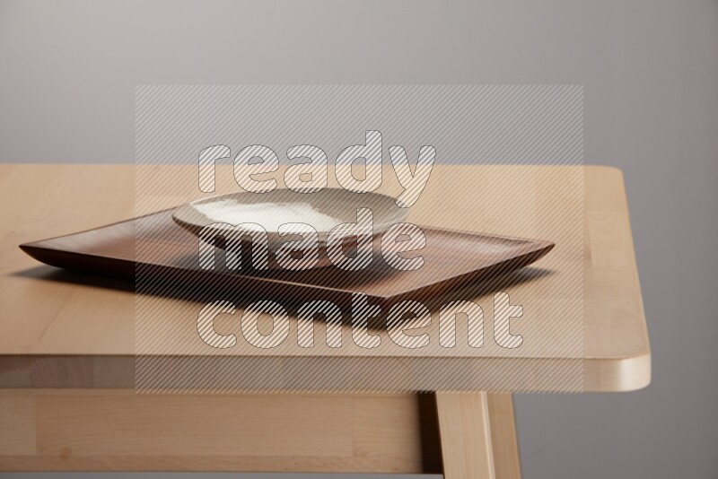 multicolored plate on a rectangular wooden tray on the edge of wooden table