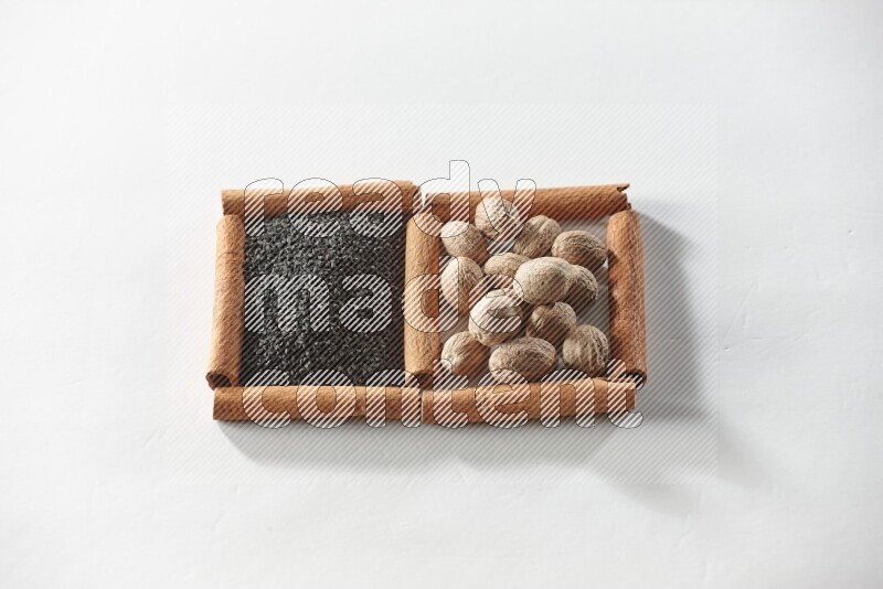 2 squares of cinnamon sticks full of black seeds and nutmeg on white flooring
