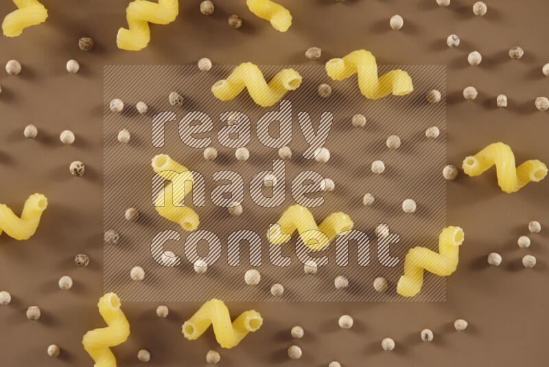 معكرونة مع مكونات متنوعة من الطماطم والثوم والبصل والفلفل الأحمر والفلفل الأسود والفلفل الأبيض وأوراق الغار وإكليل الجبل والهيل على خلفية بيج