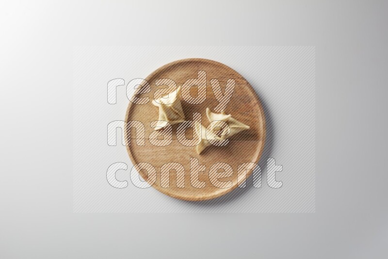 Five Sambosas on a wooden round plate on a white background