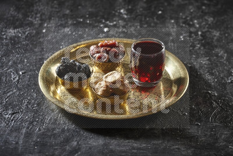 Dried fruits in metal bowls with Hibiscus on a tray in dark setup