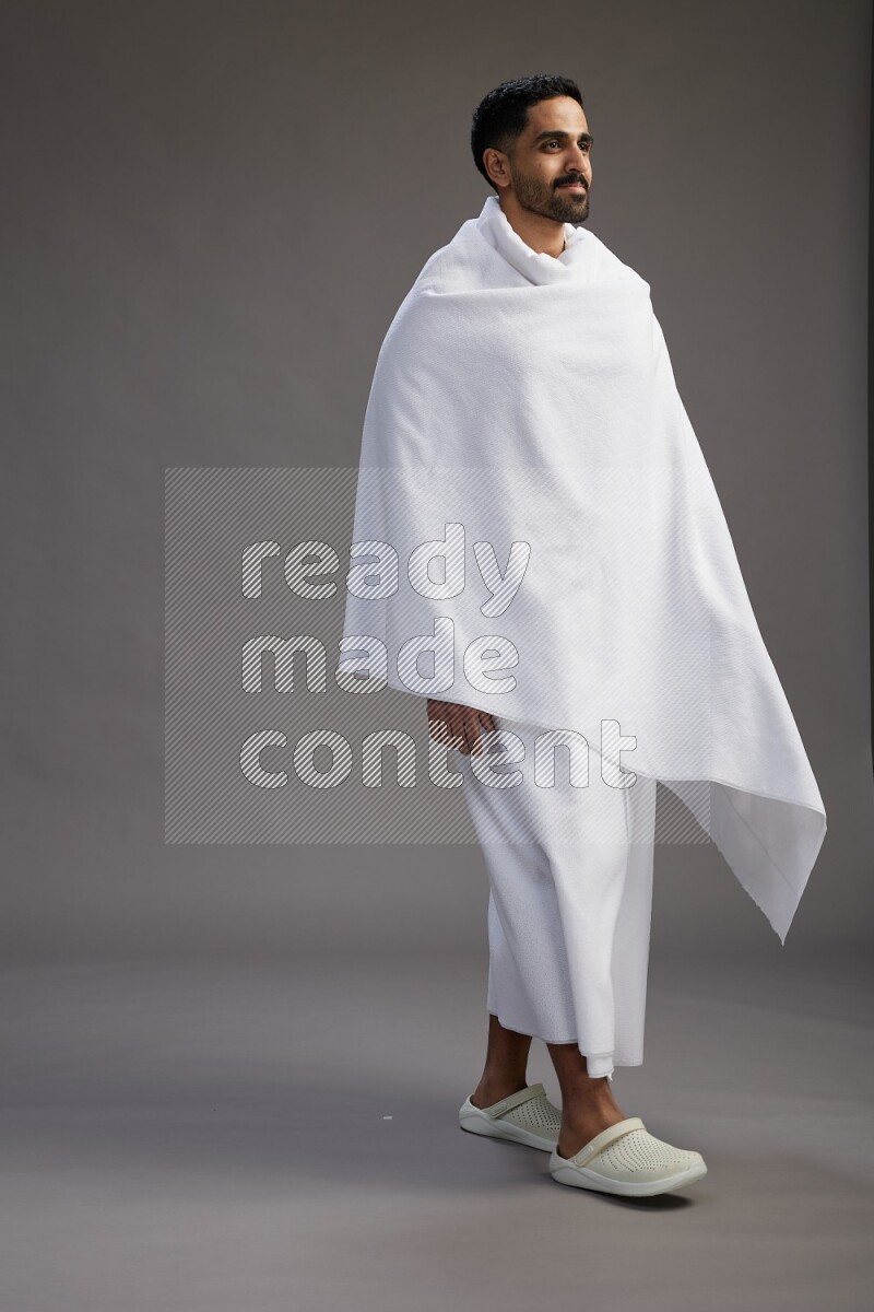 A man wearing Ehram Standing Interacting with the camera on gray background
