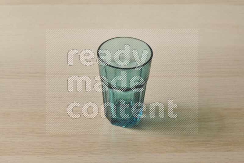 A turquoise glass cup on light wooden background