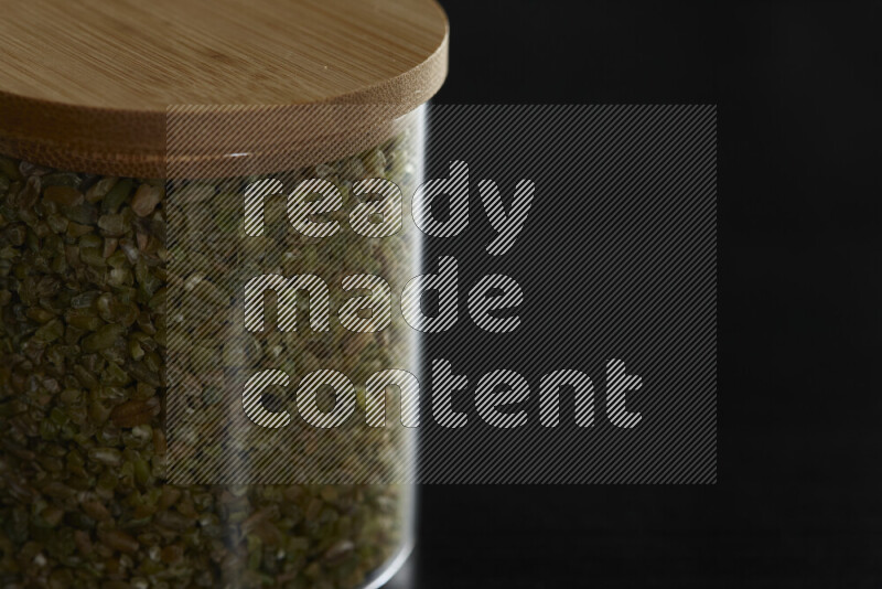 Freekeh in a glass jar on black background