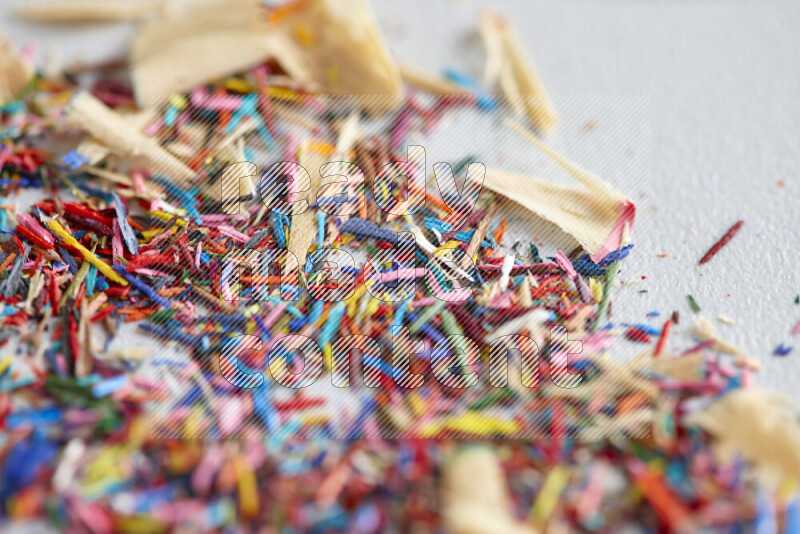 This image showcases a vibrant multicolored pencil shavings scattered on grey background