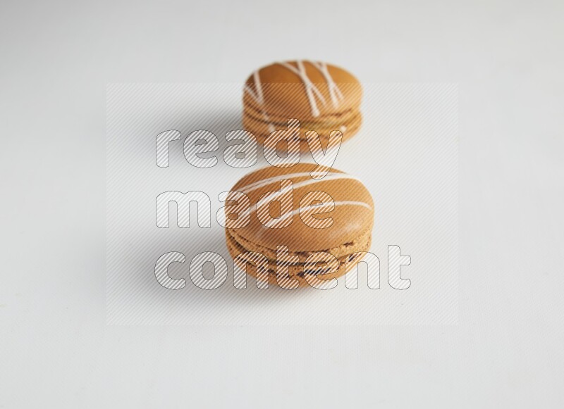 45º Shot of two Brown Irish Cream macarons on white background
