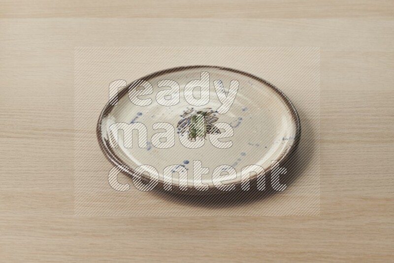 A decorative pottery plate on light wooden background