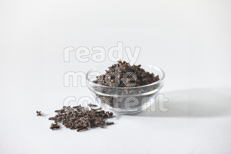 A glass bowl full of cloves on a white flooring