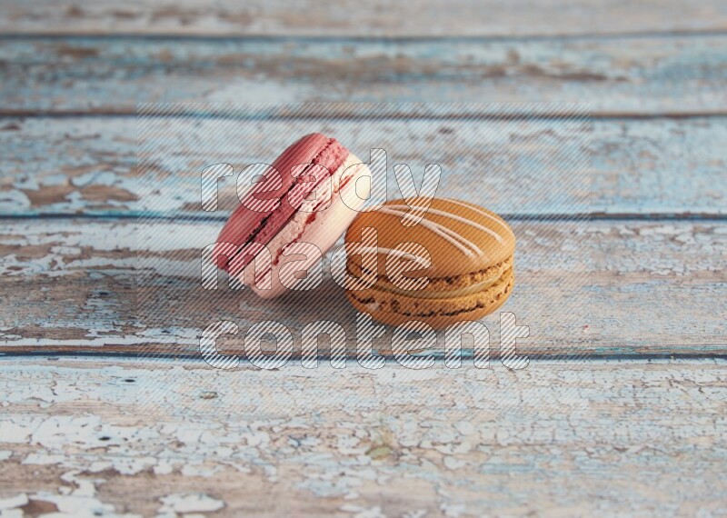 45º Shot of of two assorted Brown Irish Cream, and Pink Litchi Raspberry macarons on light blue background