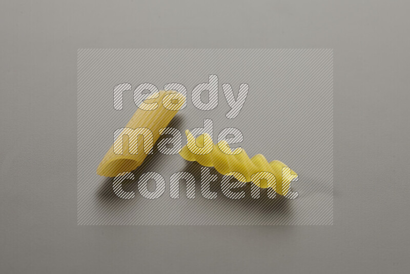 Penne pasta with other types of pasta on grey background