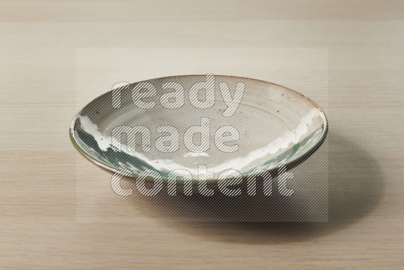 A multicolored pottery plate on light wooden background