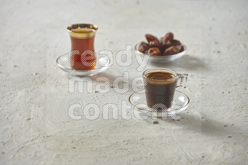 A coffee glass cup with dates and tea on textured white background