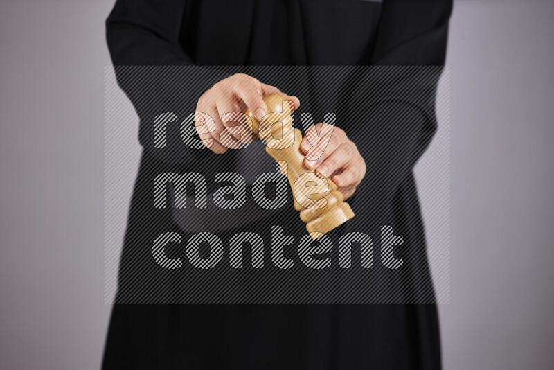 A woman in black abaya holding different wooden essentials in different positions