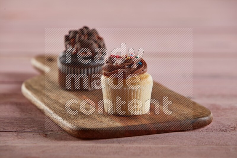 Vanilla mini cupcake topped with chocolate cream on a wooden board