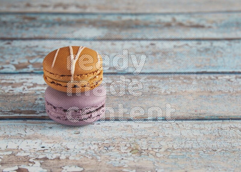 45º Shot of of two assorted Brown Irish Cream, and Purple Blueberry macarons  on light blue background