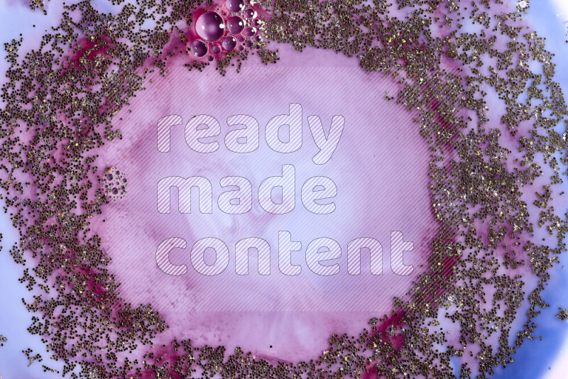 A close-up of sparkling gold glitter scattered on swirling blue and red background