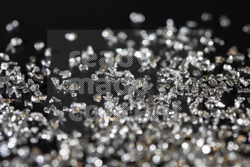 Silver shimmering fragments of glass scattered on a black background