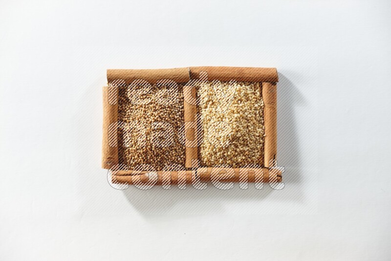 مربعان من أعواد القرفة ممتلئان بحبوب الخردل وبذور السمسم علي خلفية بيضاء
