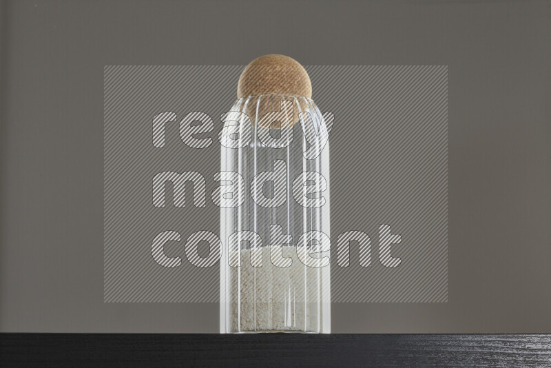 Desiccated coconut in a glass jar on black background