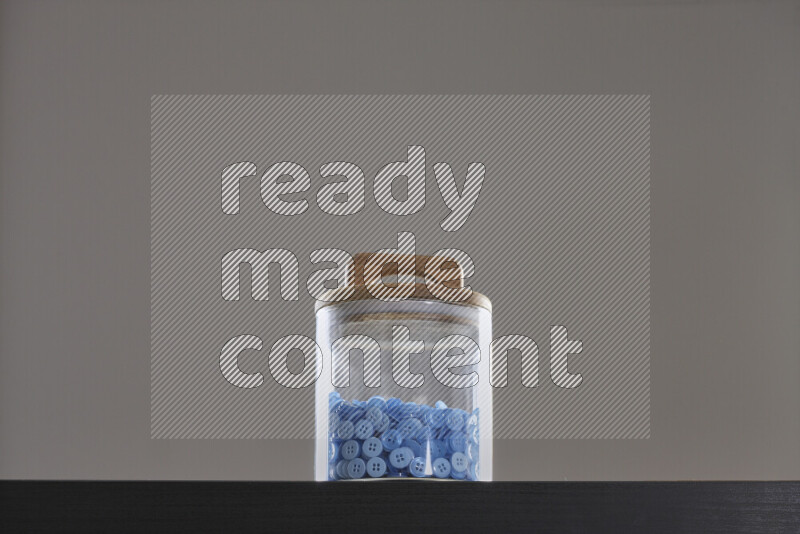 أزرار متنوعة في وعاء زجاجي علي خلفية سوداء