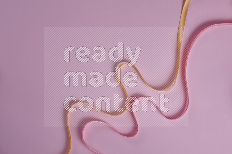 A yellow and pink collection of sewing and tailoring tools arranged on a pink background
