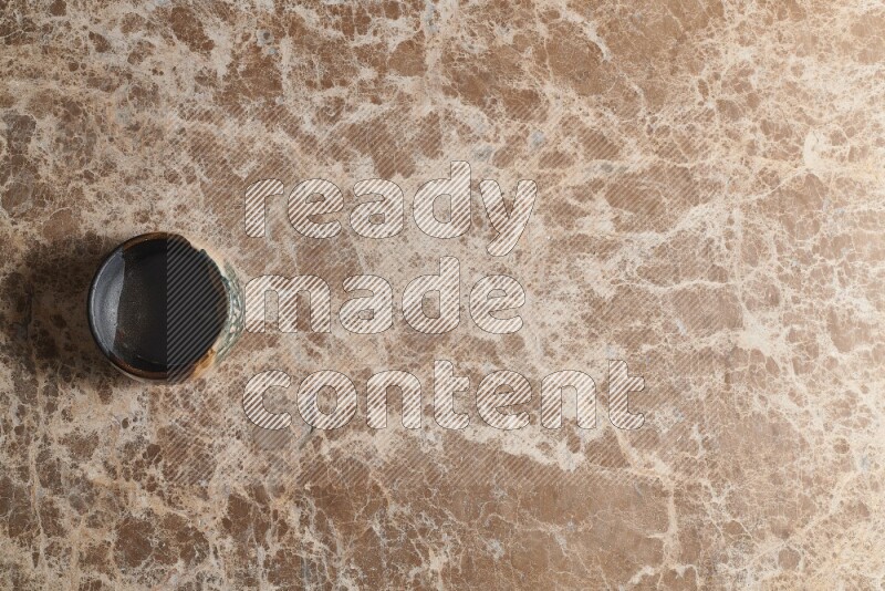 A multicolored pottery bowl on beige marble background