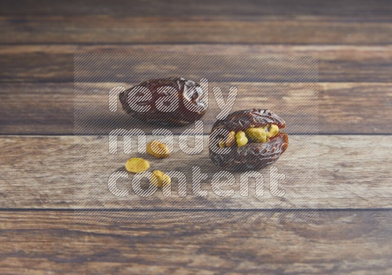 two pistachio stuffed madjoul date on a wooden background