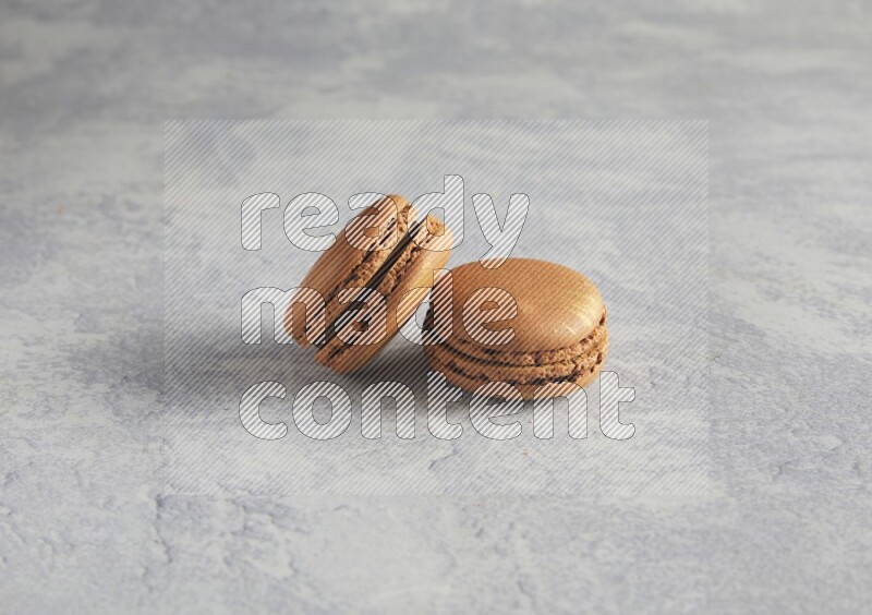 45º Shot of two Brown Coffee macarons  on white  marble background