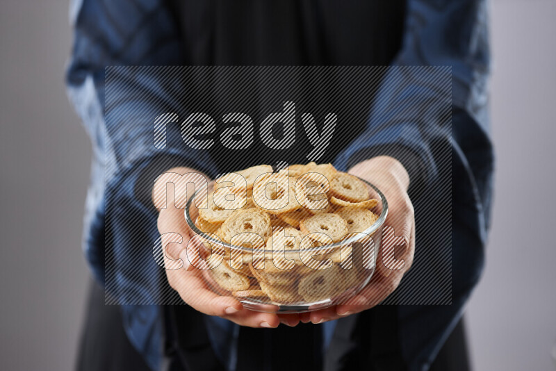 Woman in abaya holding different kinds of snacks in different positions