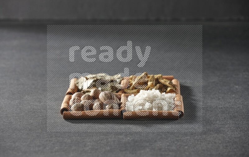 4 squares of cinnamon sticks full of bay laurel leaves, white salt, turmeric fingers and nutmegs on black flooring