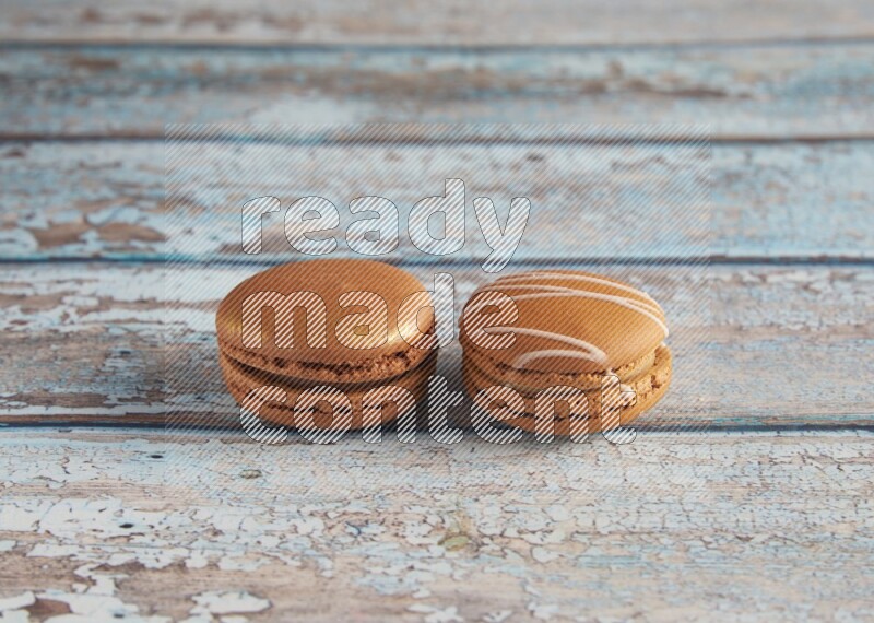 45º Shot of of two assorted Brown Irish Cream, and Brown Coffee macarons on light blue background