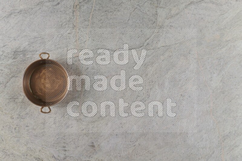 A small copper pan on grey marble background