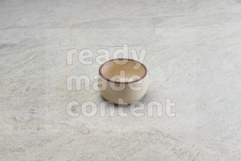 A small beige pottery bowl on grey marble background