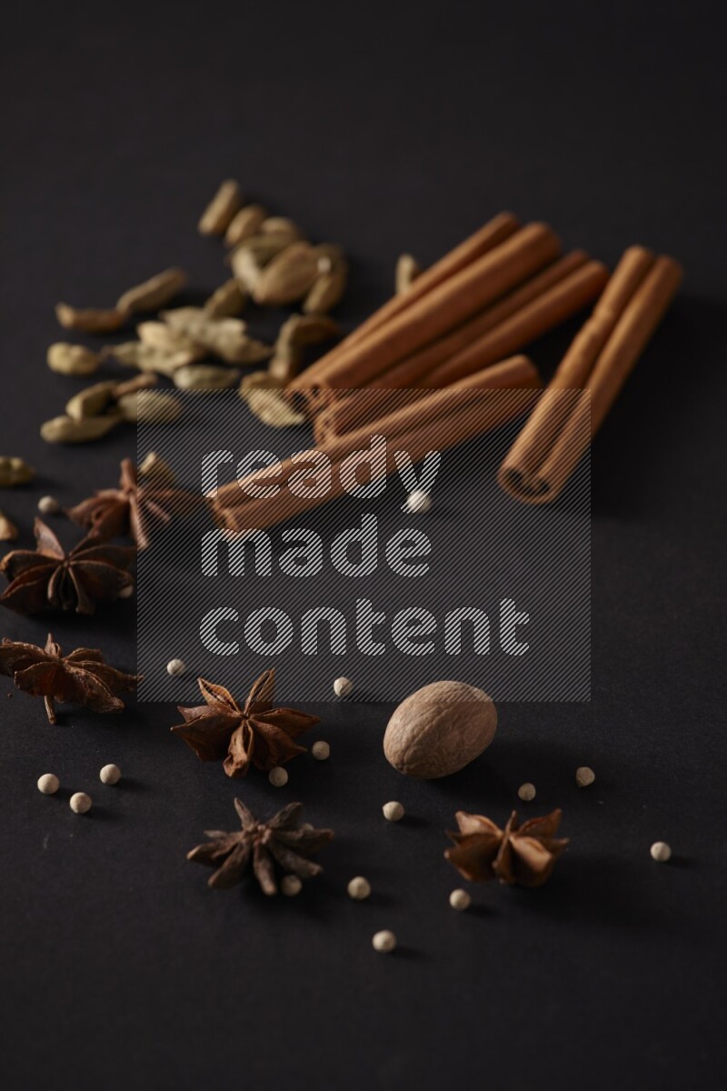 Cinnamon sticks, cardamom, star anise, nutmeg and white peppers on a black background