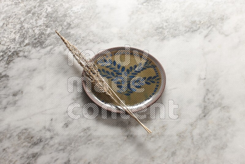 Wheat stalks on decorative pottery plate on grey marble background