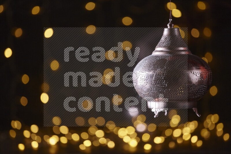 A traditional ramadan lantern surrounded by glowing fairy lights in a dark setup