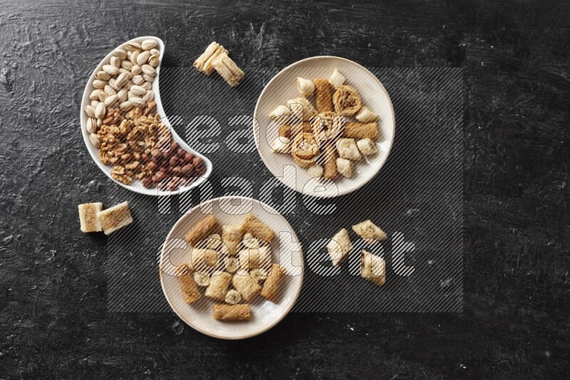 Oriental sweets in pottery plates with nuts in a dark setup